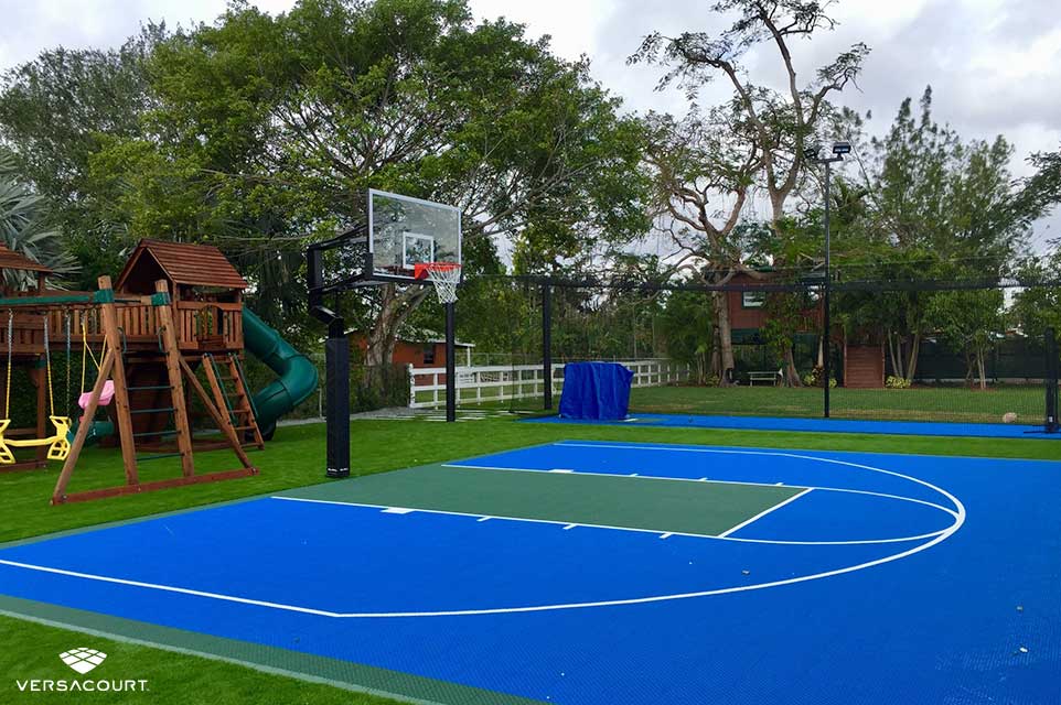 A backyard with a playground and basketball court next to it