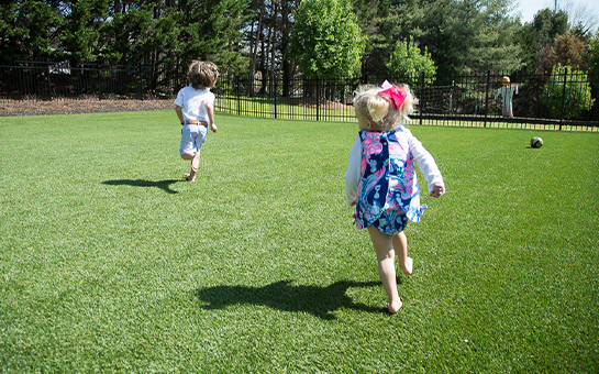 Kids running on an artificial grass lawn