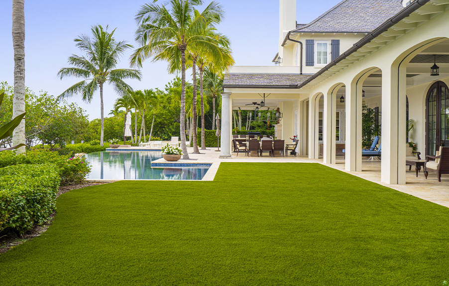 Large backyard with a swimming pool and artificial grass lawn