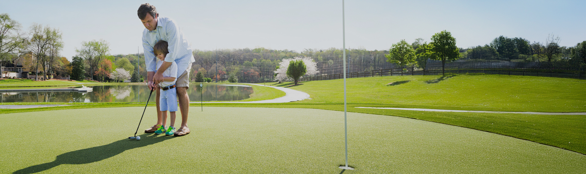 Father and child practicing putting on their backyard putting green